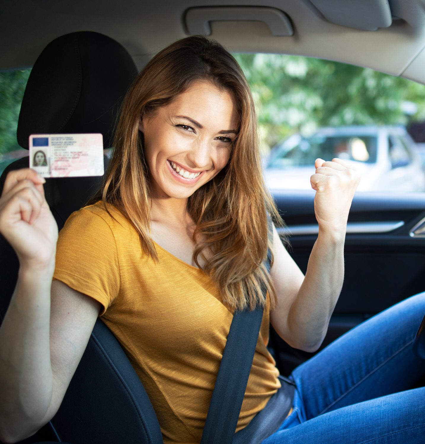 Eine Frau sitzt im Auto und zeigt ihren Führerschein